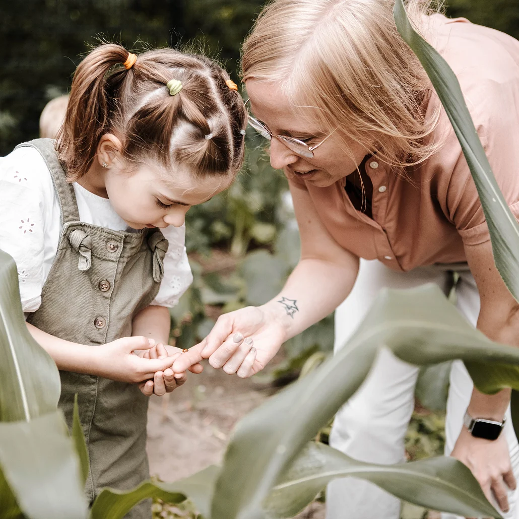 Erzieherin zeigt einem Kind einen Marienkäfer im Garten